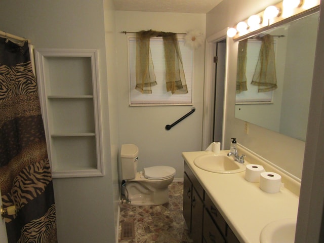 bathroom featuring toilet, a sink, and double vanity
