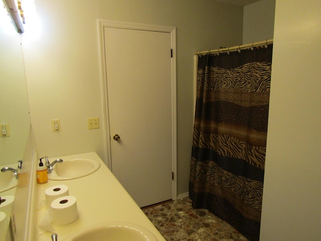 full bath with a shower with curtain, a sink, and double vanity