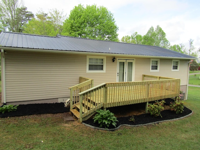 back of property with a wooden deck, a lawn, and metal roof