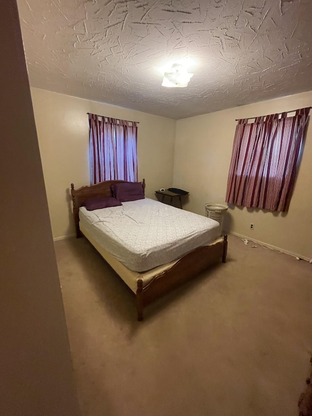 carpeted bedroom with a textured ceiling and baseboards