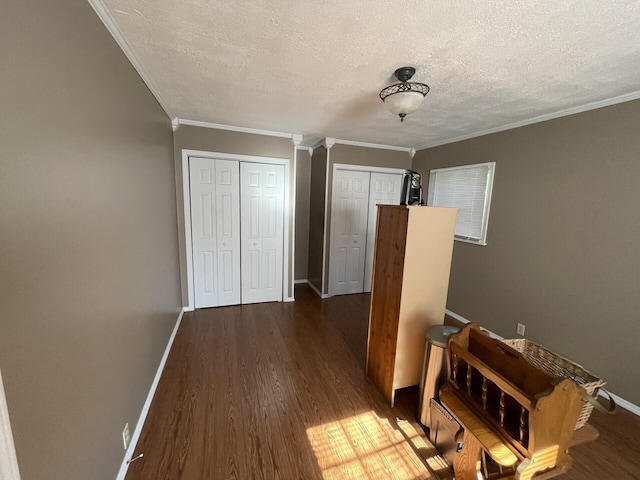hall with baseboards, a textured ceiling, crown molding, and dark wood-style floors