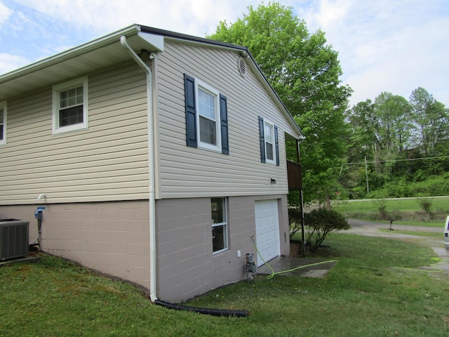 view of side of home featuring a garage, a lawn, and central AC unit