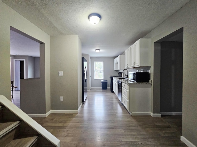 kitchen featuring dishwasher, dark wood-type flooring, sink, stainless steel fridge, and white cabinetry