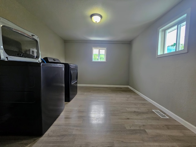 laundry room with separate washer and dryer and light hardwood / wood-style flooring