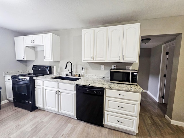 kitchen with white cabinetry, sink, light stone counters, light hardwood / wood-style floors, and black appliances