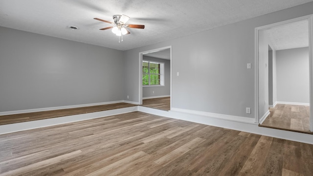 empty room featuring baseboards, a ceiling fan, a textured ceiling, and wood finished floors
