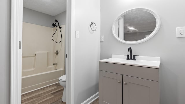 full bath with vanity, wood finished floors, toilet, a textured ceiling, and shower / washtub combination