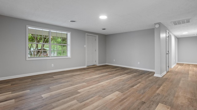 spare room with baseboards, visible vents, and wood finished floors