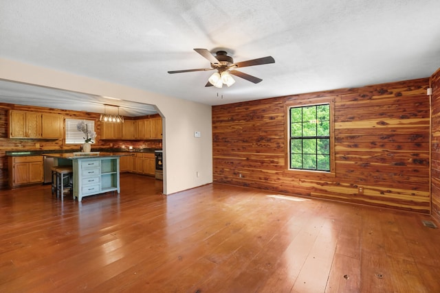148 Delph Ln, Mooresburg, TN 37811 - unfurnished living room with wood-type flooring, a ceiling fan, wood walls, and arched walkways