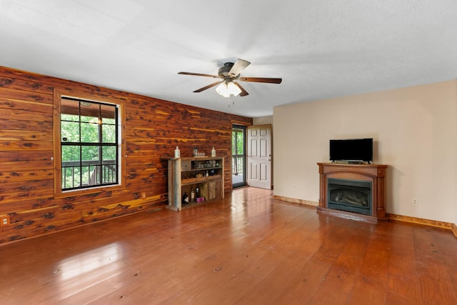 148 Delph Ln, Mooresburg, TN 37811 - unfurnished living room featuring plenty of natural light, ceiling fan, a fireplace with raised hearth, hardwood / wood-style floors, and wood walls