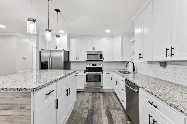 kitchen with appliances with stainless steel finishes, white cabinetry, sink, a center island, and light stone counters