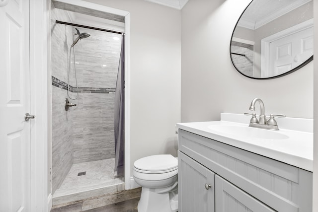 bathroom featuring toilet, crown molding, a tile shower, vanity, and hardwood / wood-style flooring