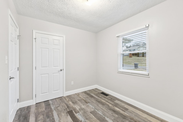 spare room featuring hardwood / wood-style floors and a textured ceiling