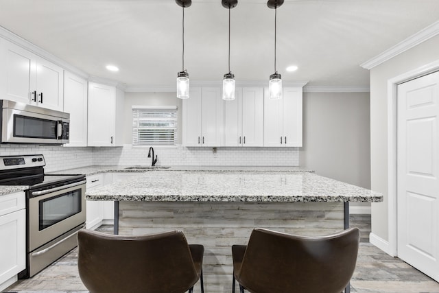 kitchen featuring appliances with stainless steel finishes, sink, light stone counters, and decorative light fixtures