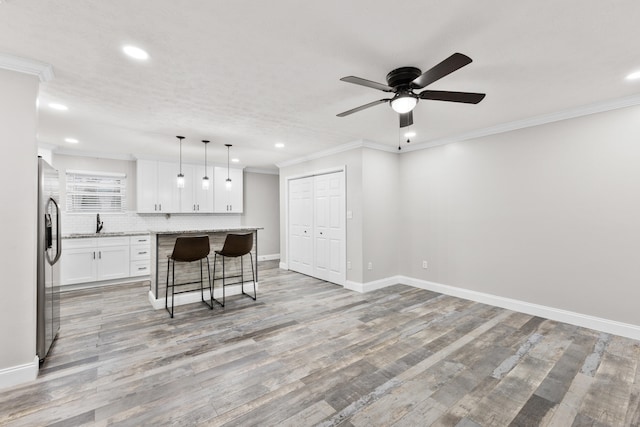 kitchen with stainless steel refrigerator with ice dispenser, a breakfast bar area, white cabinetry, a center island, and pendant lighting