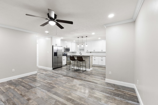 kitchen featuring stainless steel appliances, white cabinetry, a center island, and a breakfast bar area