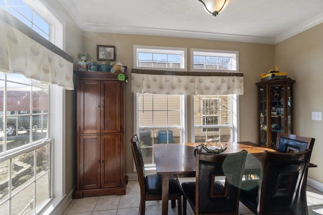 tiled dining room featuring crown molding and a healthy amount of sunlight