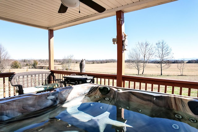 deck featuring ceiling fan, a rural view, and a hot tub