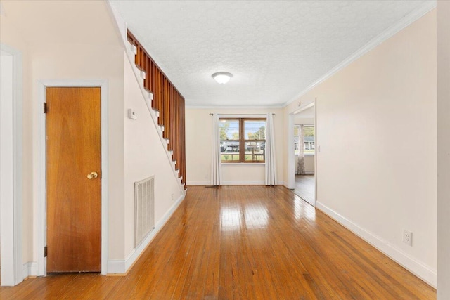 interior space with light hardwood / wood-style floors, ornamental molding, and a textured ceiling