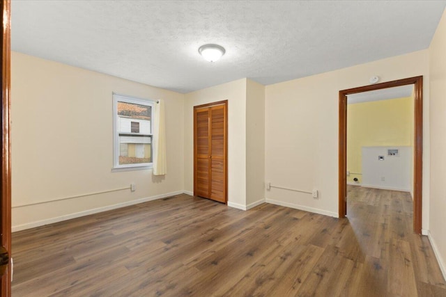 unfurnished bedroom with a textured ceiling, dark hardwood / wood-style floors, and a closet