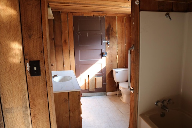 full bathroom featuring washtub / shower combination, wooden walls, vanity, and toilet