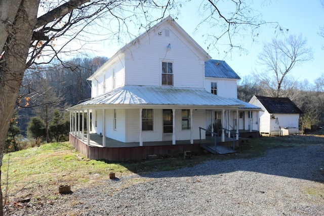 farmhouse featuring covered porch and an outdoor structure