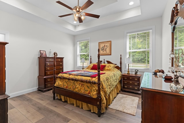 bedroom featuring a raised ceiling, ceiling fan, and light hardwood / wood-style floors