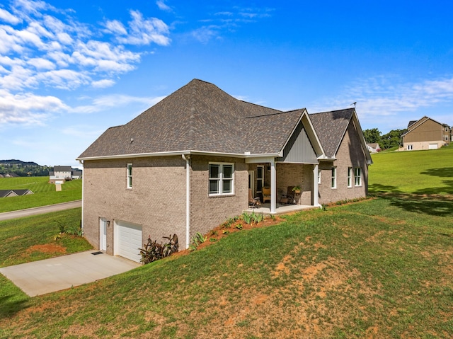 back of property with a patio, a garage, and a lawn