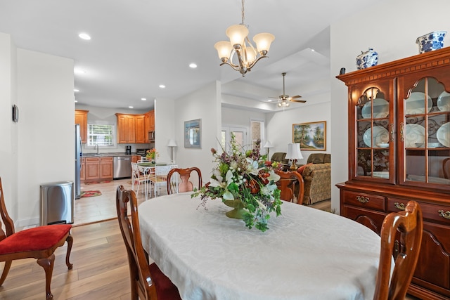 dining space featuring ceiling fan with notable chandelier, light hardwood / wood-style floors, and sink