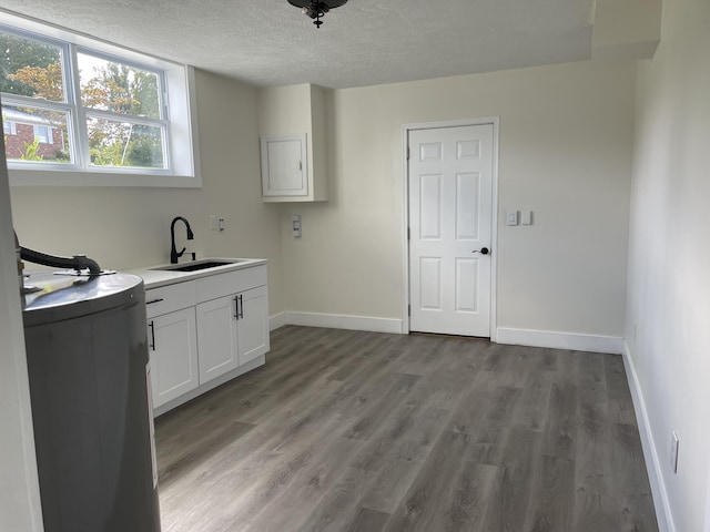 laundry room featuring a textured ceiling, light wood finished floors, a sink, and baseboards