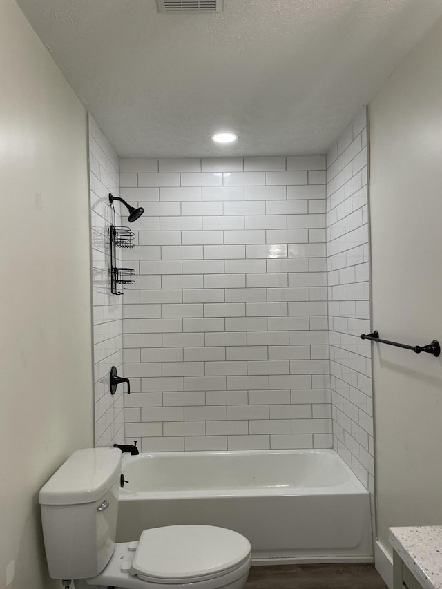 full bathroom featuring vanity, hardwood / wood-style floors, tiled shower / bath, and toilet