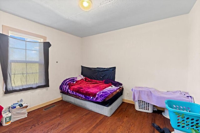 bedroom with wood finished floors, visible vents, and baseboards