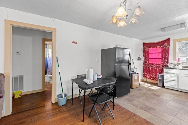dining room featuring light wood-type flooring, visible vents, baseboards, and an inviting chandelier