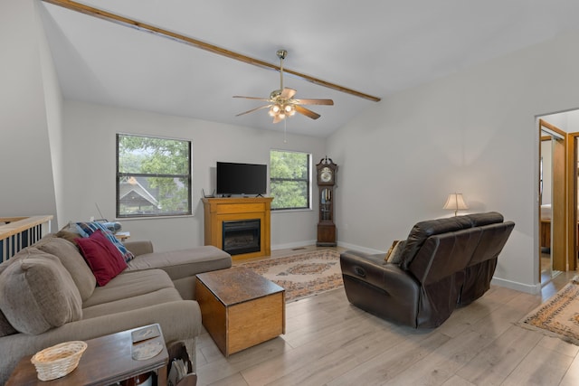 living area with light wood-type flooring, a ceiling fan, a glass covered fireplace, baseboards, and vaulted ceiling