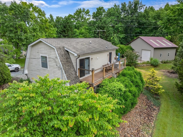 back of house with a shingled roof, a gambrel roof, a garage, an outdoor structure, and a deck