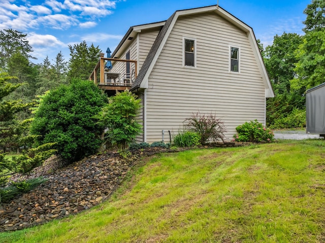 view of property exterior featuring a yard, a gambrel roof, and a deck