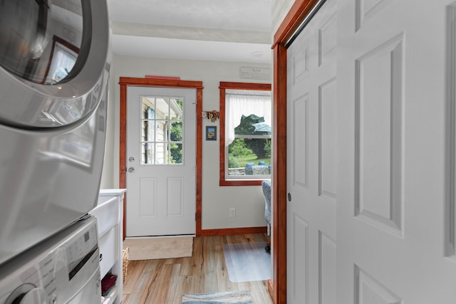 entrance foyer with baseboards, stacked washer / drying machine, and light wood-style floors