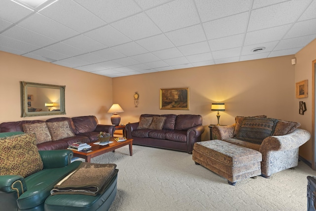 living area with a paneled ceiling, carpet floors, and visible vents