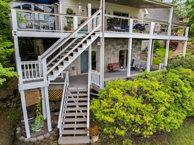 rear view of house featuring stone siding and stairs