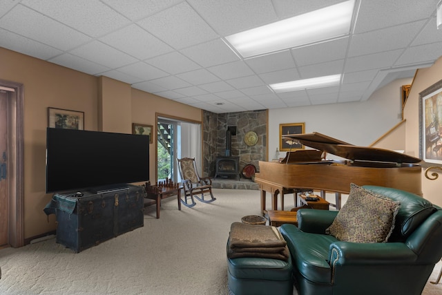 living room with a drop ceiling, a wood stove, and carpet floors