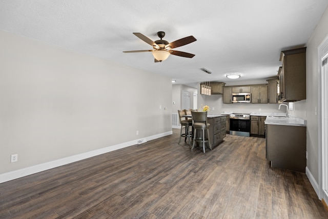 kitchen with a kitchen island, a breakfast bar, sink, dark hardwood / wood-style flooring, and stainless steel appliances