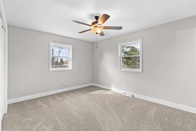 carpeted empty room with a wealth of natural light and ceiling fan