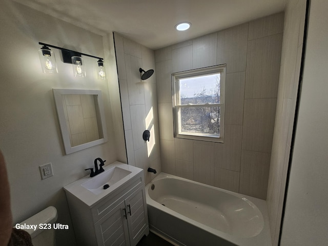 full bathroom featuring tiled shower / bath, vanity, and toilet