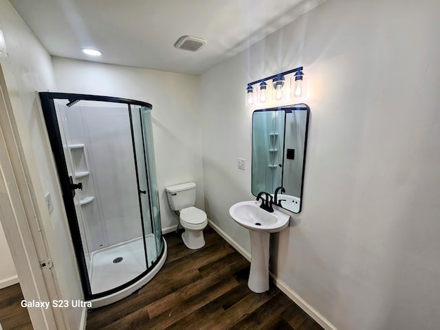 bathroom with sink, hardwood / wood-style flooring, a shower with shower door, and toilet