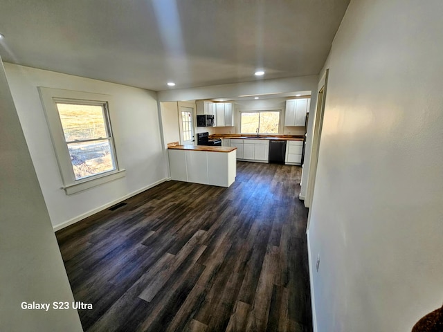 kitchen featuring dark hardwood / wood-style flooring, black appliances, wooden counters, and white cabinets