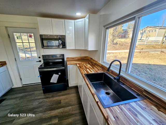 kitchen featuring butcher block countertops, sink, white cabinets, black range with electric cooktop, and dark wood-type flooring