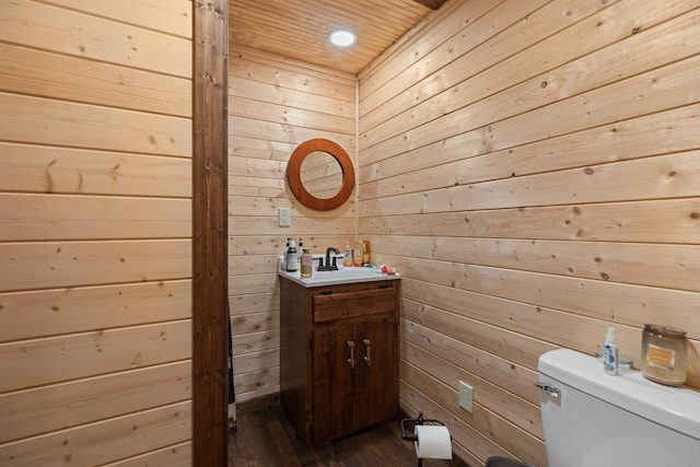 bathroom featuring vanity, toilet, wooden ceiling, and wood walls