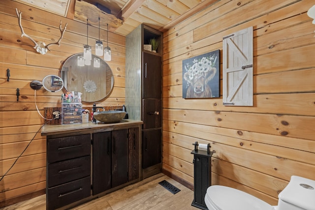 bathroom featuring wooden ceiling, hardwood / wood-style floors, toilet, wooden walls, and vanity