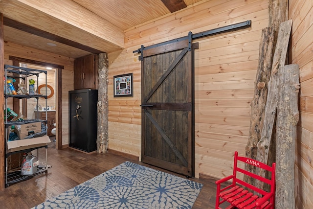 interior space featuring a barn door, dark hardwood / wood-style floors, and wooden walls