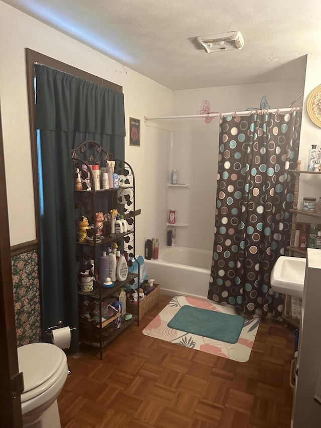 full bathroom featuring sink, shower / bathtub combination with curtain, parquet flooring, a textured ceiling, and toilet